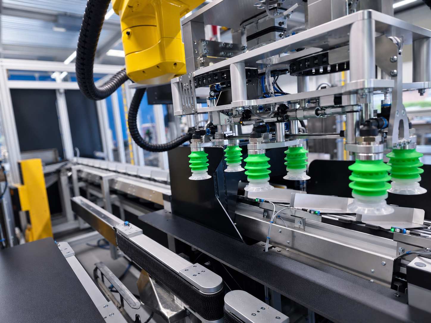 Industriële robotarm met groene vacuümgrijpers boven een transportband in een geautomatiseerde verpakkingslijn.